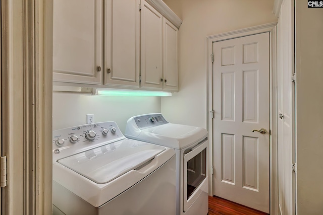 clothes washing area featuring washing machine and dryer, dark hardwood / wood-style flooring, and cabinets