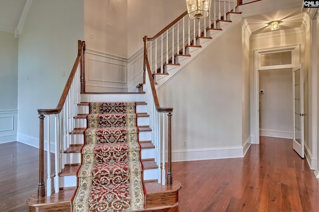 stairs featuring hardwood / wood-style flooring, a notable chandelier, and ornamental molding