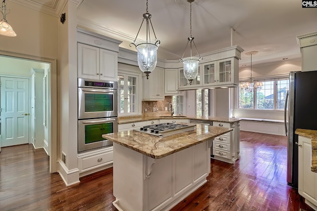 kitchen featuring sink, hanging light fixtures, stainless steel appliances, a kitchen island, and white cabinets