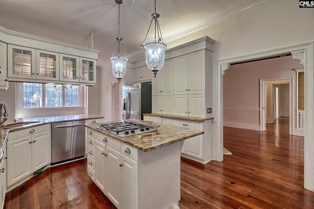 kitchen featuring appliances with stainless steel finishes, sink, a center island, white cabinetry, and hanging light fixtures