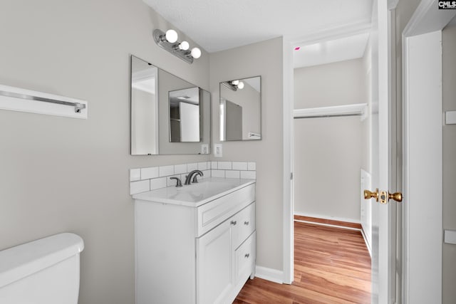 bathroom with toilet, vanity, a textured ceiling, and hardwood / wood-style flooring