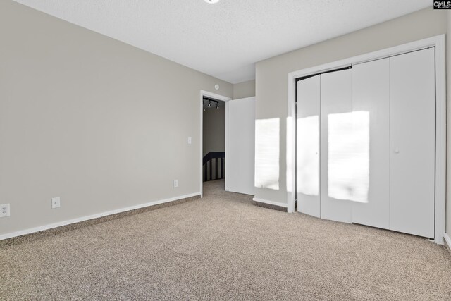 unfurnished bedroom with a textured ceiling, carpet floors, and a closet