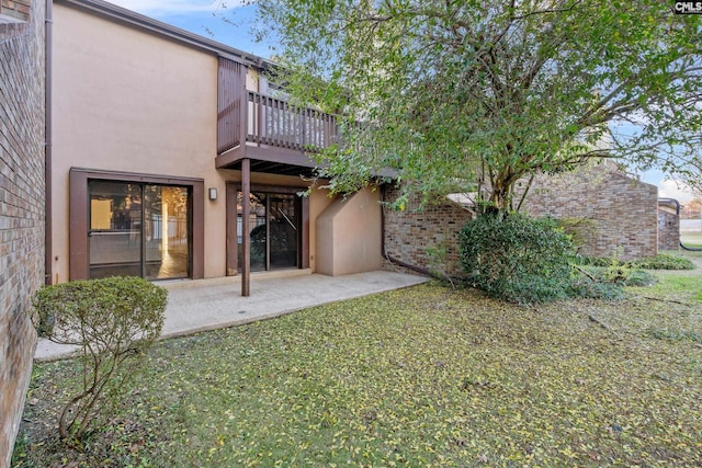 back of property featuring a patio area, a yard, and a balcony