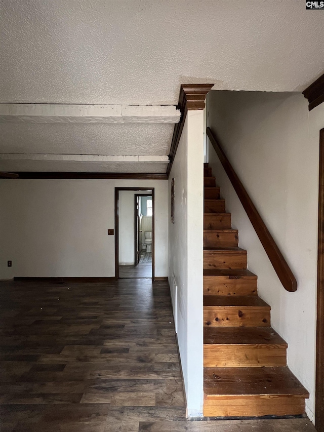 stairway with beam ceiling, a textured ceiling, and hardwood / wood-style flooring