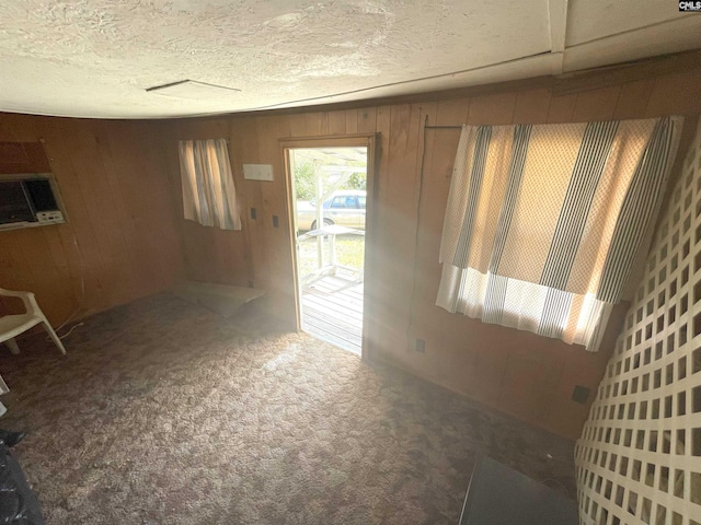 carpeted empty room with a textured ceiling and wooden walls