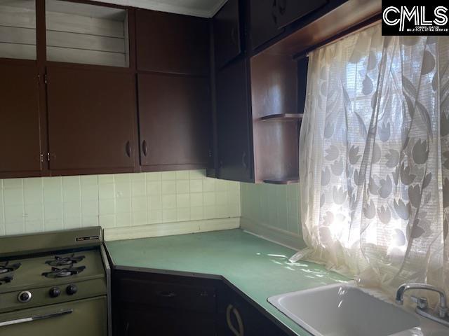 kitchen featuring decorative backsplash, stove, and sink