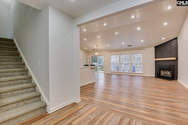 unfurnished living room featuring a large fireplace, light hardwood / wood-style flooring, and sink