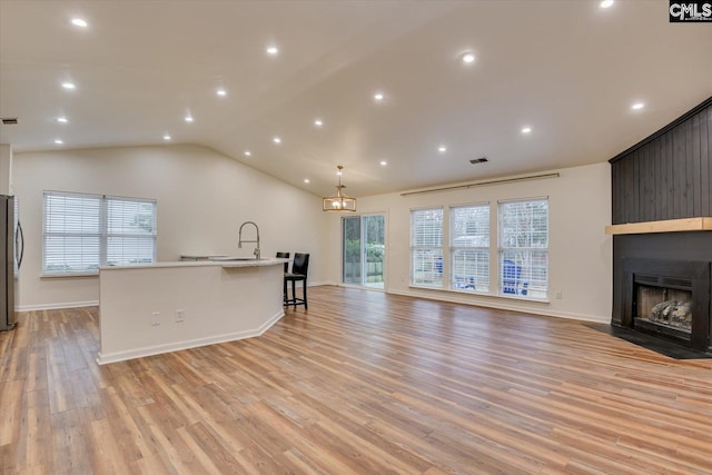 unfurnished living room with a large fireplace, light hardwood / wood-style floors, and vaulted ceiling