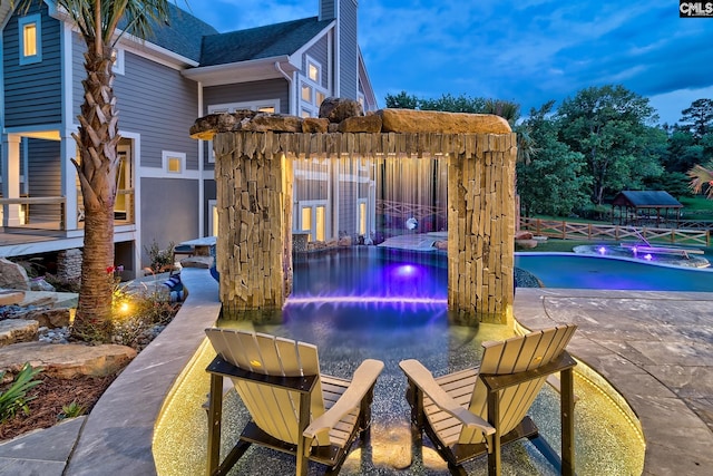 pool at dusk featuring an outdoor pool and a patio