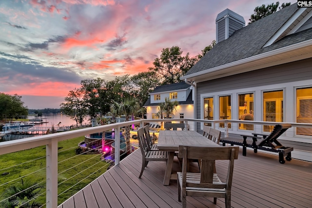 deck with a yard, outdoor dining area, and a water view