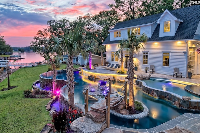 outdoor pool with a patio area, a water view, and a yard