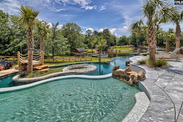 view of swimming pool with a water view and fence