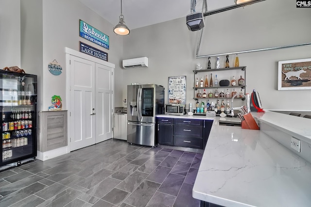 kitchen with pendant lighting, appliances with stainless steel finishes, an AC wall unit, light stone countertops, and beverage cooler