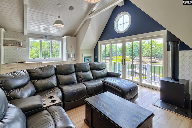 living room with vaulted ceiling with beams, light wood finished floors, and a wealth of natural light