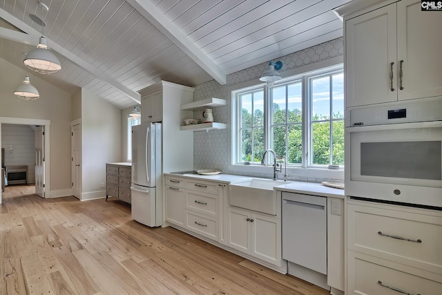 kitchen featuring lofted ceiling with beams, white appliances, a sink, white cabinetry, and light countertops