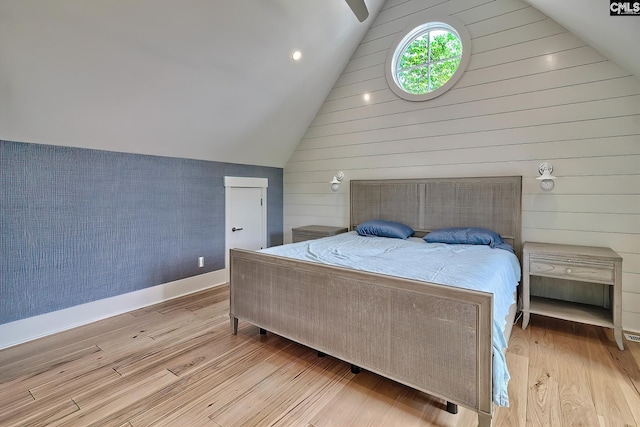 bedroom with lofted ceiling, light wood-style flooring, and baseboards