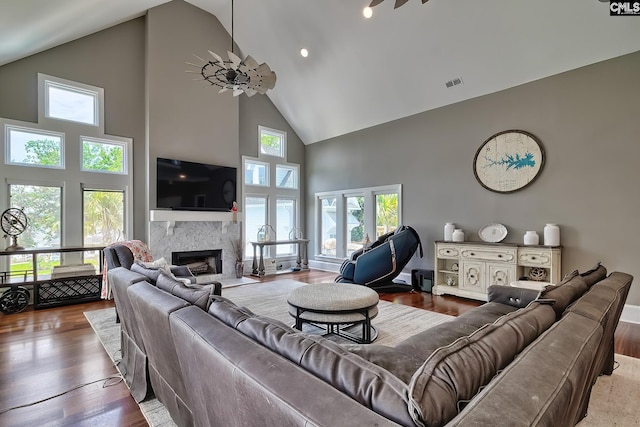 living room featuring ceiling fan, high vaulted ceiling, a fireplace, wood finished floors, and visible vents