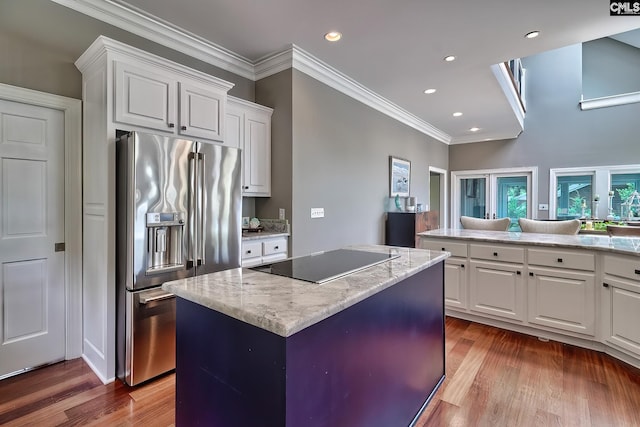 kitchen with black electric stovetop, high quality fridge, white cabinetry, and a center island