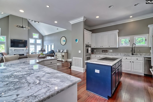 kitchen with stainless steel appliances, open floor plan, white cabinets, a kitchen island, and a sink