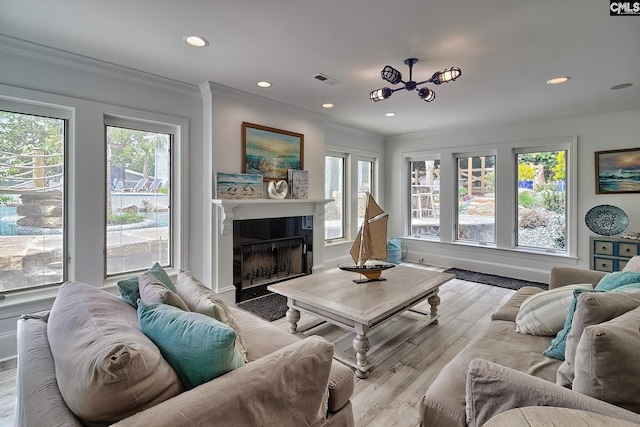 living area with light wood-type flooring, crown molding, visible vents, and a wealth of natural light