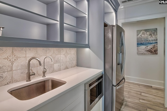 kitchen featuring a sink, light countertops, stainless steel refrigerator with ice dispenser, backsplash, and open shelves