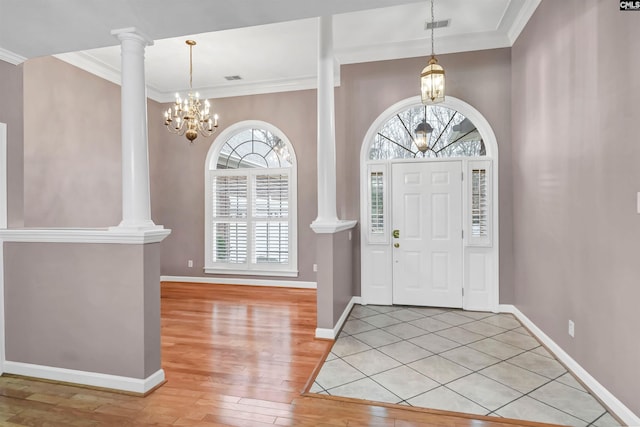 foyer entrance featuring decorative columns, a wealth of natural light, and an inviting chandelier