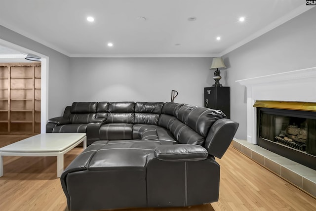 living room with light hardwood / wood-style flooring, ornamental molding, and a tiled fireplace