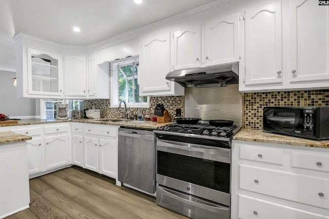 kitchen featuring white cabinetry, sink, stainless steel appliances, light hardwood / wood-style flooring, and backsplash