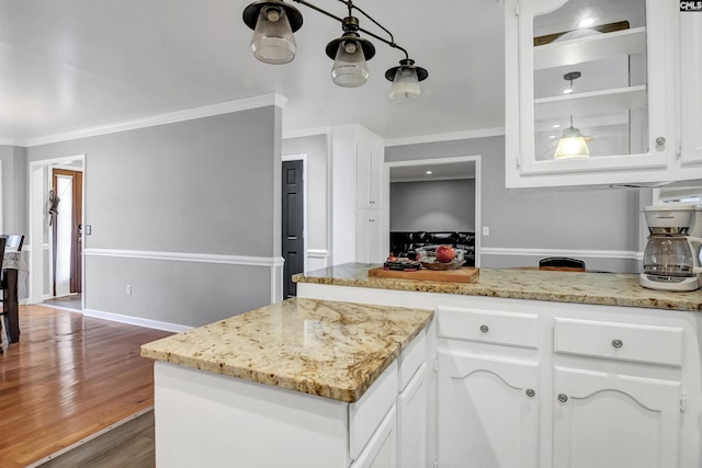 kitchen featuring light stone countertops, dark hardwood / wood-style flooring, white cabinetry, and crown molding