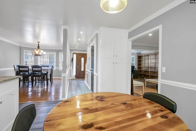 dining space with wood-type flooring, a notable chandelier, and ornamental molding