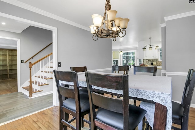 dining space featuring crown molding, light wood-type flooring, and an inviting chandelier