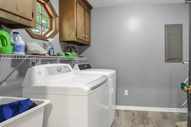 clothes washing area with cabinets, electric panel, sink, washing machine and dryer, and a textured ceiling