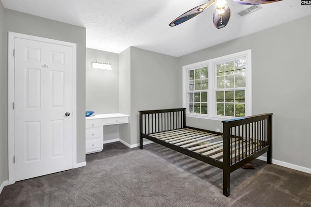 carpeted bedroom with ceiling fan, a textured ceiling, and a nursery area