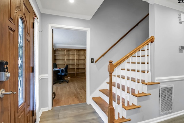 foyer with light hardwood / wood-style floors and crown molding