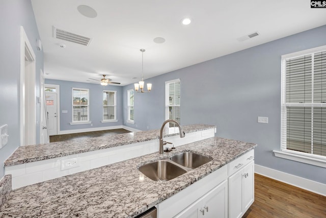 kitchen featuring white cabinetry, light stone countertops, sink, and hanging light fixtures