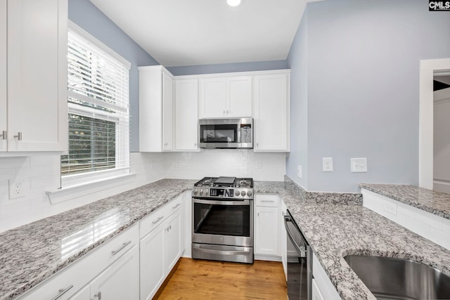 kitchen featuring stainless steel appliances, white cabinetry, and light stone counters