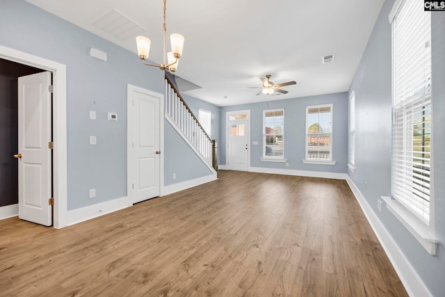 unfurnished living room featuring ceiling fan with notable chandelier and light wood-type flooring