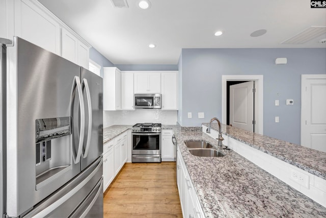 kitchen with white cabinetry, sink, light stone countertops, and stainless steel appliances