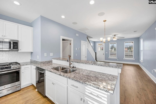 kitchen with white cabinetry, sink, hanging light fixtures, kitchen peninsula, and appliances with stainless steel finishes