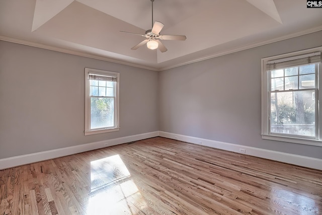 empty room with ceiling fan, crown molding, light hardwood / wood-style flooring, and a tray ceiling