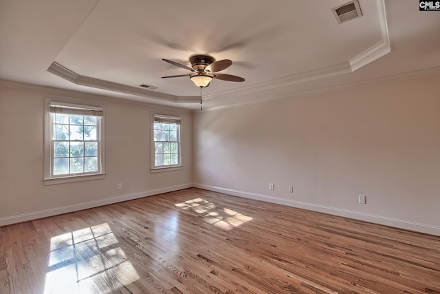 spare room featuring ceiling fan, a raised ceiling, light wood-type flooring, and ornamental molding