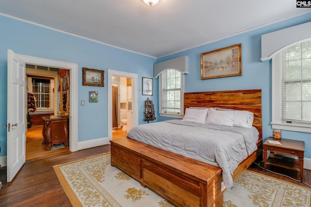 bedroom with ensuite bathroom, dark hardwood / wood-style floors, and ornamental molding