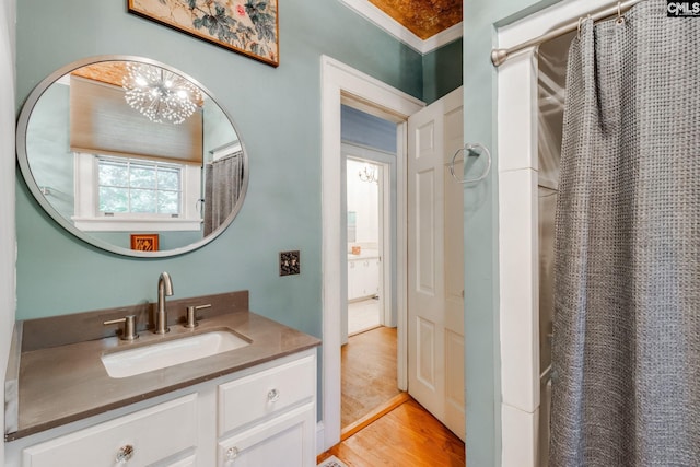 bathroom with a chandelier, crown molding, vanity, and wood-type flooring