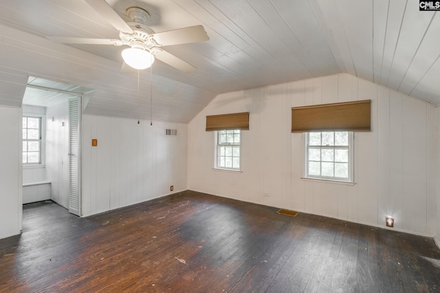 empty room featuring ceiling fan, wood walls, dark hardwood / wood-style flooring, and vaulted ceiling