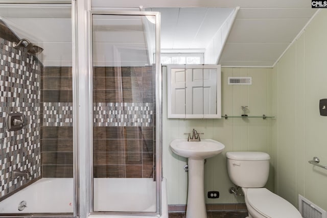 bathroom with toilet, a shower with shower door, and sink