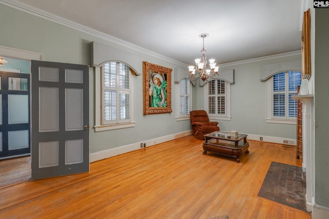 sitting room with light wood-type flooring, ornamental molding, and an inviting chandelier