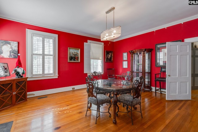 dining room with wood-type flooring and crown molding