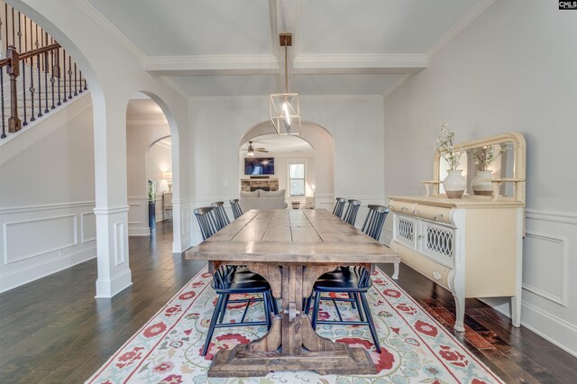 dining room with a fireplace, ceiling fan, dark wood-type flooring, crown molding, and beamed ceiling