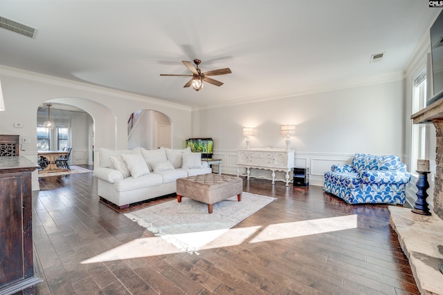 living room with dark hardwood / wood-style flooring, ceiling fan, and crown molding