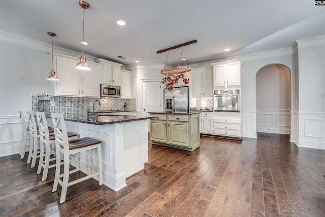 kitchen featuring decorative backsplash, appliances with stainless steel finishes, kitchen peninsula, dark stone countertops, and hanging light fixtures